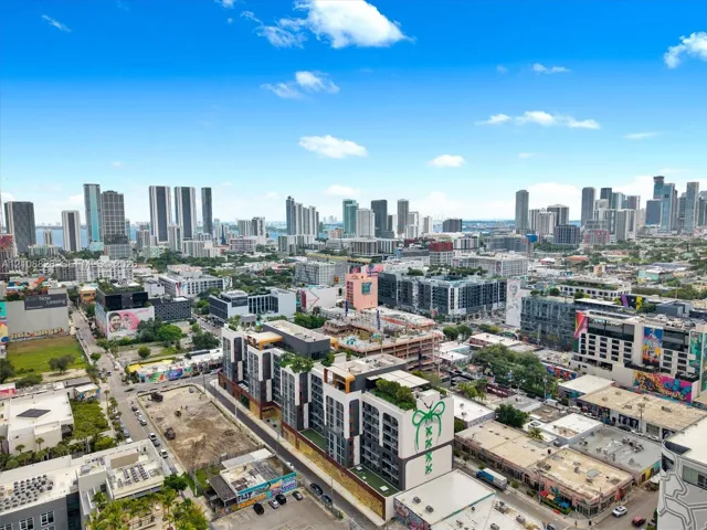Aerial perspective of an urban setting featuring a multi-story building with a rooftop terrace and high-density skyline