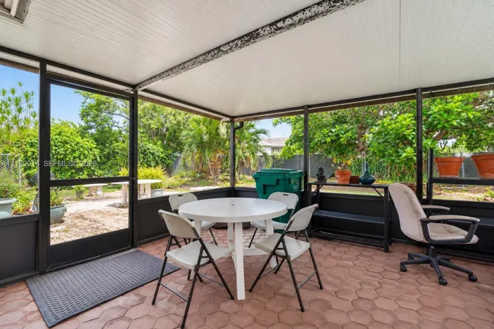 Screened-in patio featuring hexagonal paver flooring, a solid white ceiling, and dark metal framing