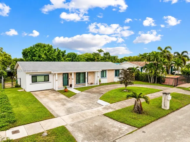Single-story residence featuring a covered front porch, stone-accented facade, concrete driveway, and expansive lawn