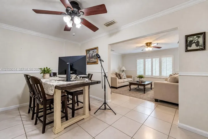 Neutral tile flooring, ceiling fans with integrated light kits, crown molding, chair rail trim, and plantation shutters