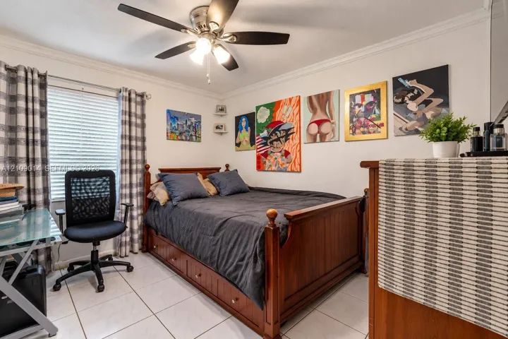 Light-colored tile flooring, crown molding, ceiling fan with integrated light fixture, and corner shelving units