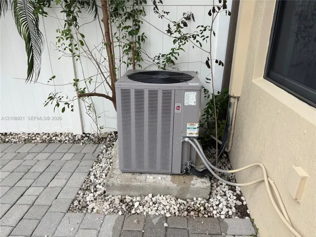 Exterior HVAC unit set on a concrete pad, surrounded by gravel ground cover and a concrete paver patio
