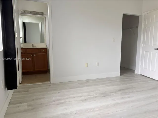 Wood-finish flooring, multi-panel interior door, and walk-in closet featuring wire shelving
