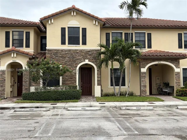 Stucco exterior featuring decorative stone masonry, arched entryways, tile roof, and shuttered windows