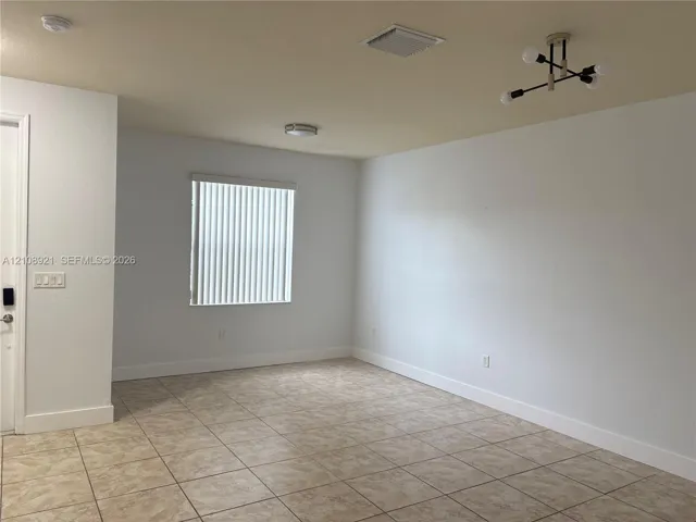 Neutral-toned ceramic tile flooring, multi-arm structural light fixture, and vertical window blinds