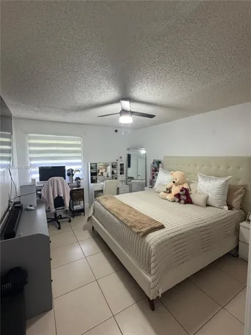 Room featuring large-format ceramic tile flooring, a ceiling fan with integrated lighting, and a multi-tiered window shade