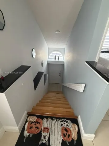 Staircase featuring wood-finish treads, stone-topped wall ledges, and a semi-circular transom window