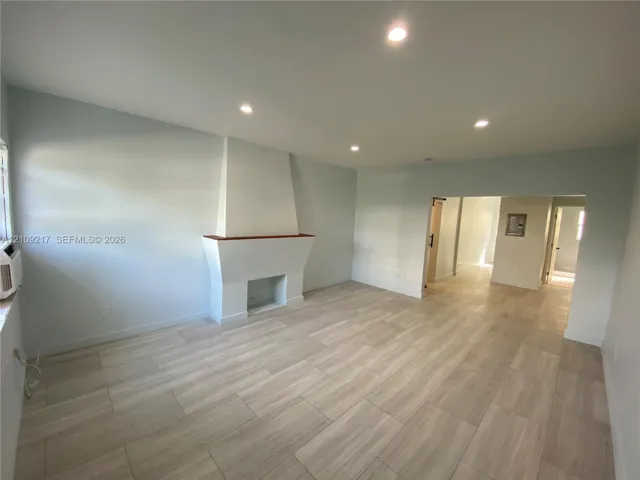 Living area featuring wood-finish flooring, recessed lighting, and a prominent fireplace with a wood mantel