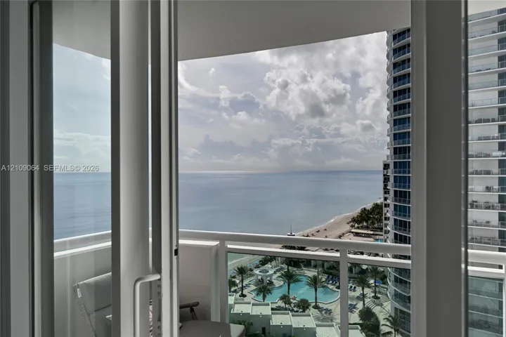 Private covered balcony featuring white railing and floor-to-ceiling glass sliding doors