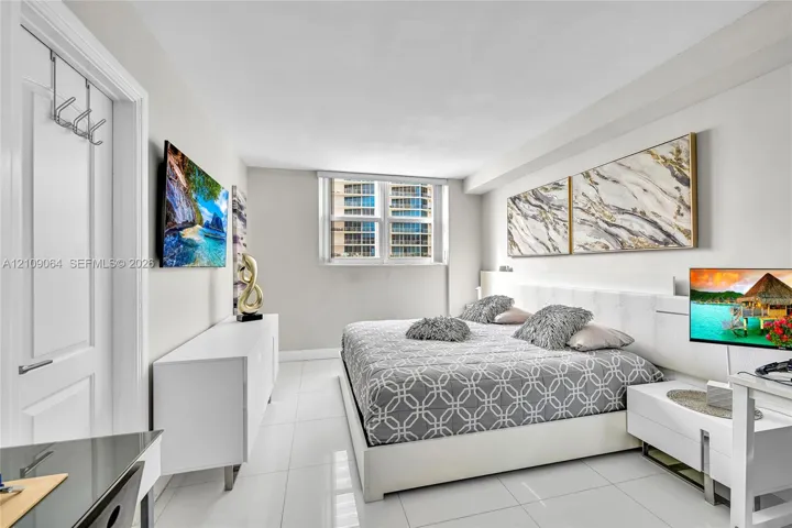 Neutral-toned interior featuring large-format tile flooring, a multi-panel window, and a built-in recessed headboard wall panel