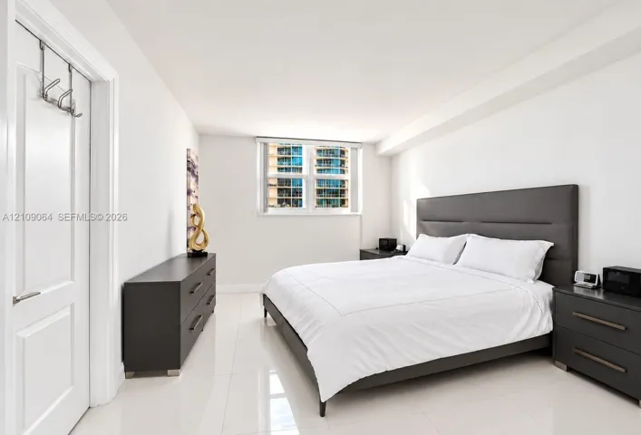 Bright bedroom featuring polished tile flooring, crisp white walls, and a large window