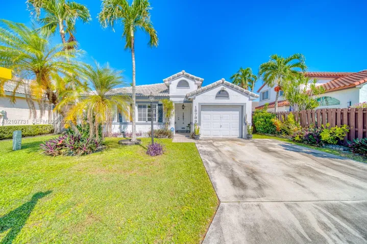 Stucco exterior featuring a tiled roof, arched architectural accents, an attached one-car garage, and established landscaping with mature palm trees