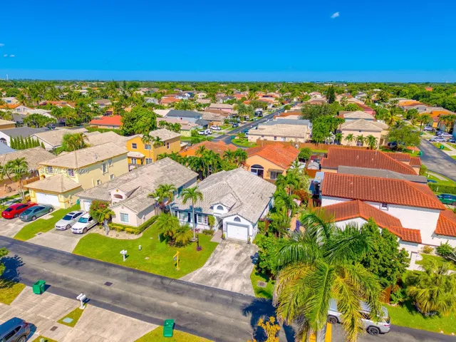 Single-story residence featuring a tile roof, paved driveway, one-car garage, and established landscaping