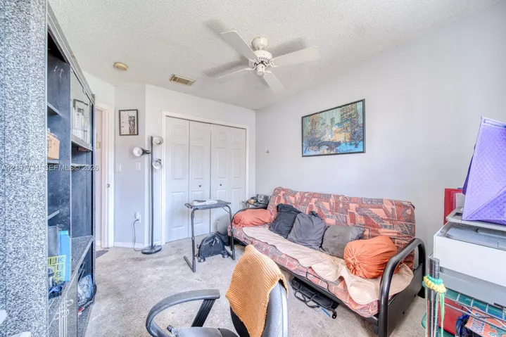 Room featuring a ceiling fan, wall-to-wall carpeting, and double-door closet cabinetry