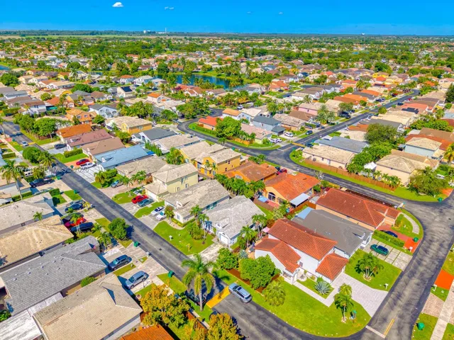 Aerial perspective of a residential community featuring curvilinear street layouts, established landscaping, dense greenery, and concrete paved driveways