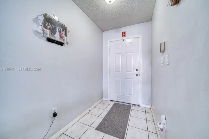Entryway featuring tile flooring, a six-panel exterior door, and a textured ceiling finish