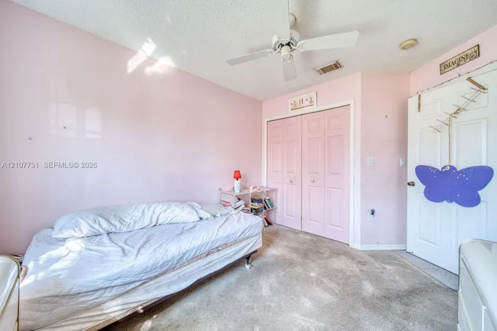 Room featuring neutral-toned carpeting, dual-panel closet doors, and a ceiling-mounted fan with integrated lighting
