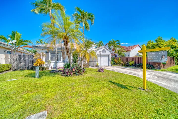 Single-story residence featuring a tile roof, light-toned stucco exterior, integrated garage, and landscaped front yard with mature palm trees