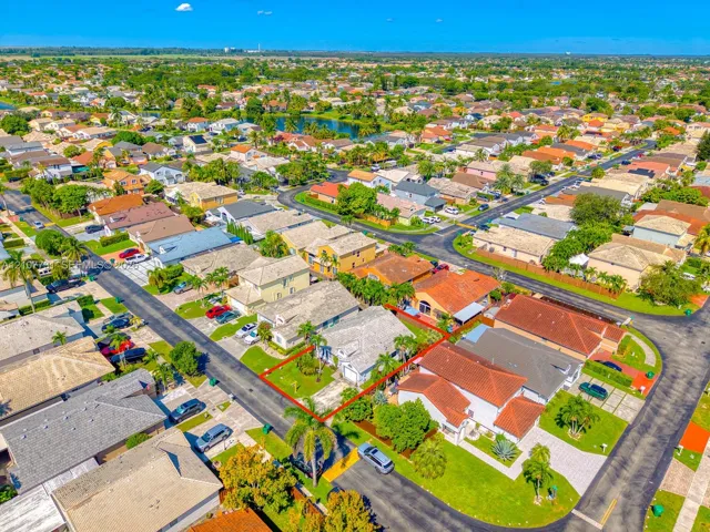 Aerial perspective of a single-story residence featuring a concrete tile roof, attached garage, paved driveway, and landscaped front yard