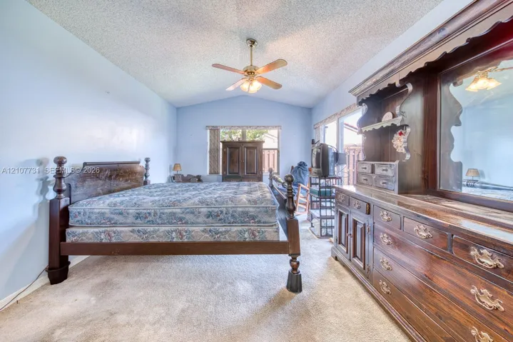 Vaulted ceiling featuring a central brass-finish ceiling fan with integrated lighting and neutral carpeting