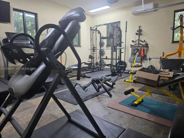 Multipurpose room featuring tile flooring, multiple windows, and a wall-mounted ductless heating and cooling unit