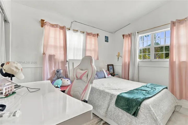 Bedroom featuring white wall finish, multi-pane windows, and chair rail molding