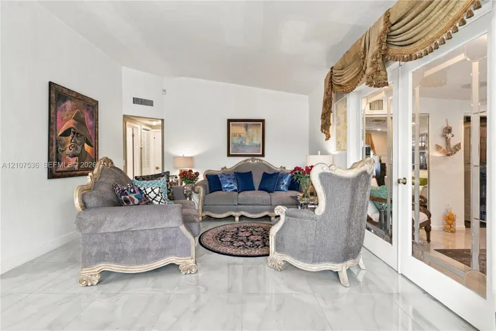 High-gloss tile flooring, vaulted ceilings, and glass-paneled double doors featuring brass hardware