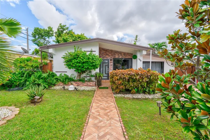 Mid-century modern architectural style featuring a low-pitched roofline, stone veneer facade accent, and a dedicated herringbone-patterned paved walkway