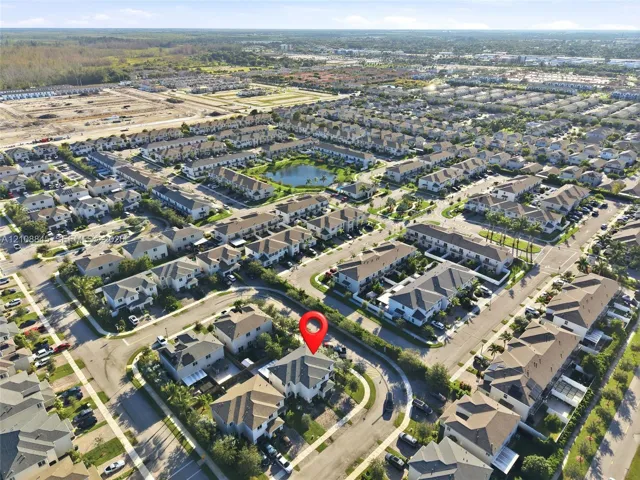 Aerial perspective of a multi-story residence featuring a hipped roof and a corner lot configuration within a residential community