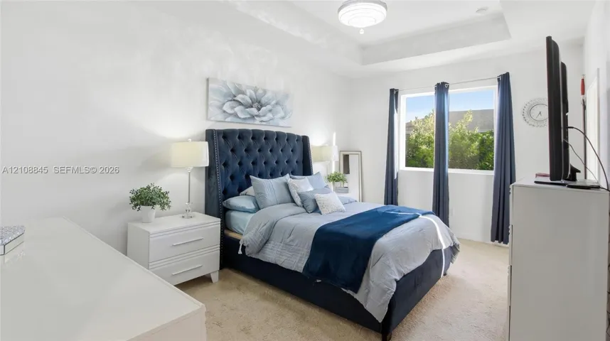 Tray ceiling, neutral wall tones, plush wall-to-wall carpeting, and a flush-mount light fixture