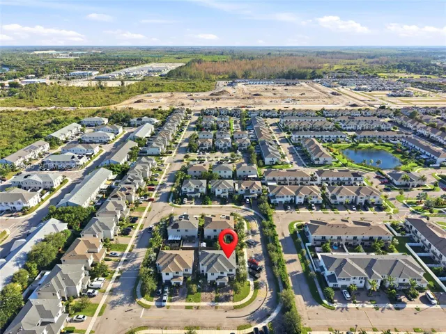 Aerial perspective of a multi-unit residential community featuring paved roads, uniform architectural design, and localized green spaces