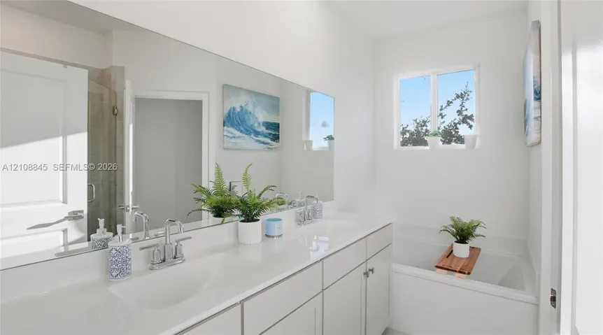 Dual-sink vanity with a solid-surface countertop, full-width wall mirror, and integrated soaking tub