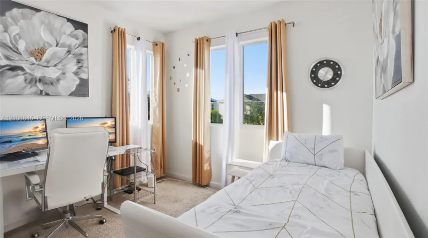 Bedroom featuring plush carpeting, neutral wall color, and multiple windows with drapery hardware