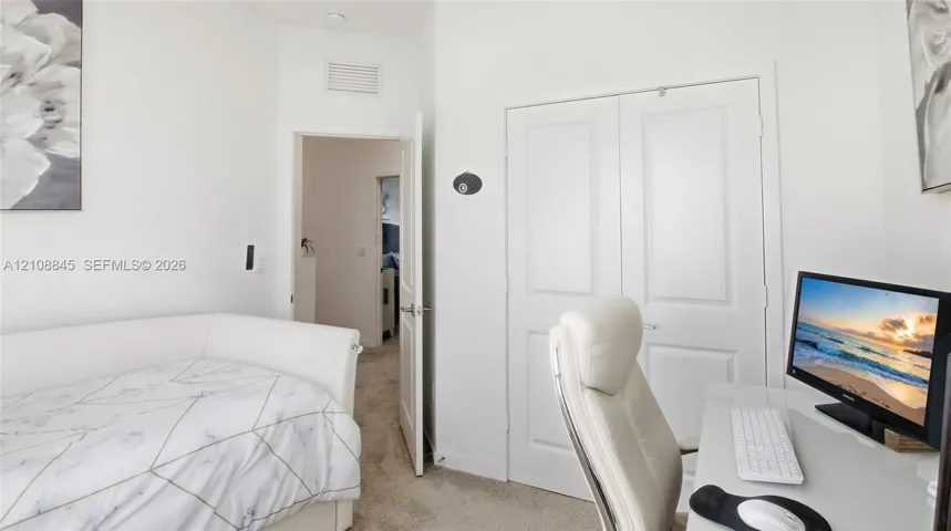 Interior space featuring neutral-toned carpeting, white walls, and a double-door reach-in closet