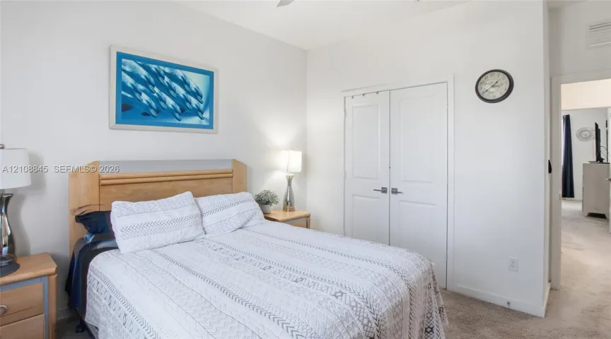 Neutral-toned interior featuring carpeting, dual-panel closet doors with satin-finish hardware, and a ceiling fan
