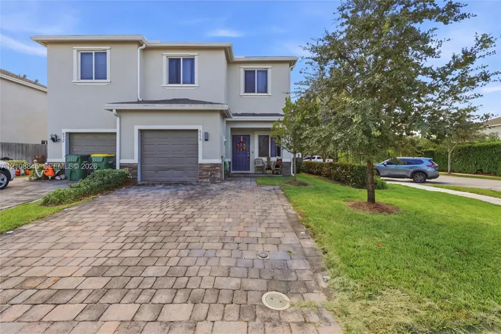 Two-story exterior featuring a paver driveway, stone facade accents, an integrated garage, and a covered entry