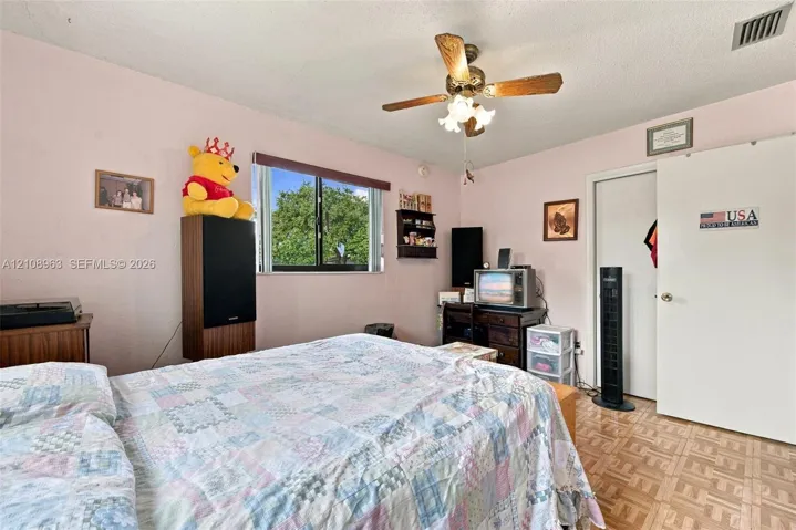 Bedroom featuring a multi-light ceiling fan, sliding window, and parquet flooring