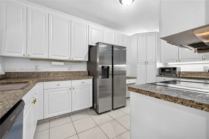 Kitchen featuring white cabinetry, stone-surface countertops, tile flooring, and stainless steel appliances