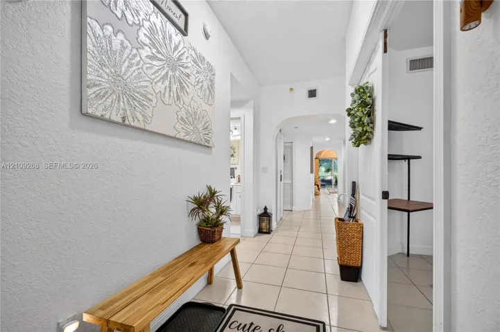 Neutral tile flooring, arched architectural passageways, and a built-in pantry with integrated shelving