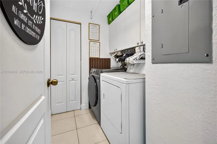 Laundry area featuring tile flooring, white shaker-style wall cabinetry, and a bi-fold closet door