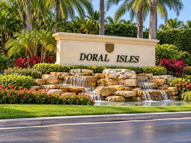 Community monument sign featuring multi-tiered natural stone water features, integrated landscaping, and mature palm trees