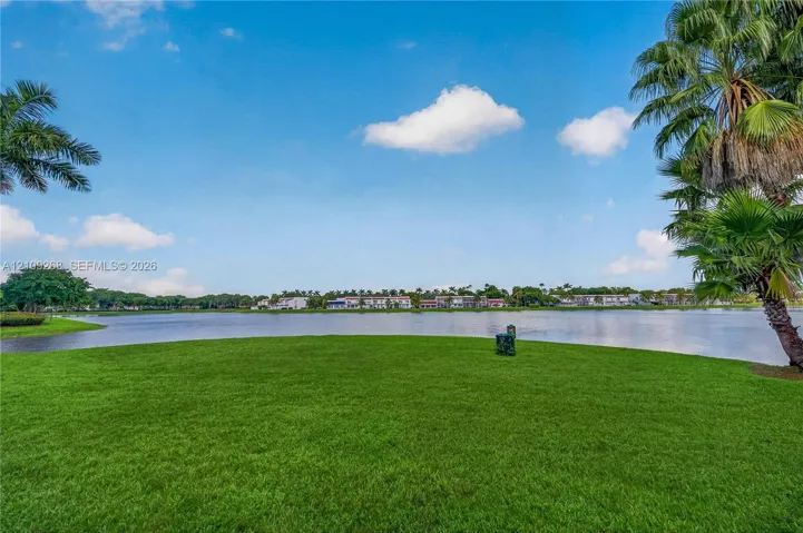 Expansive lawn featuring mature palm trees and direct waterfront frontage