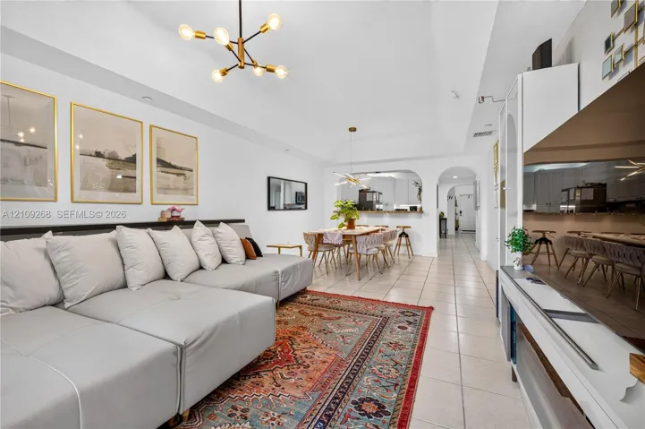 Vaulted ceilings, large-format tile flooring, multi-arm chandelier lighting, and arched doorways