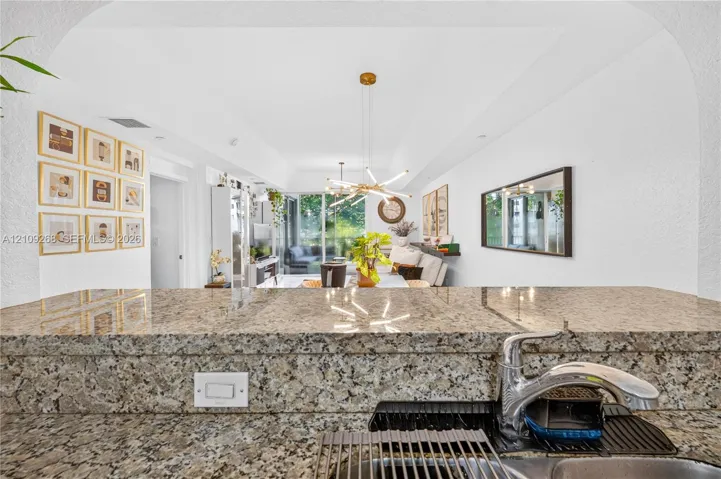 Stone countertop featuring a polished finish, stainless steel faucet, and arched ceiling entry