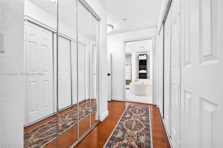 Hallway featuring wood-finish flooring, floor-to-ceiling mirrored sliding closet doors, and recessed lighting