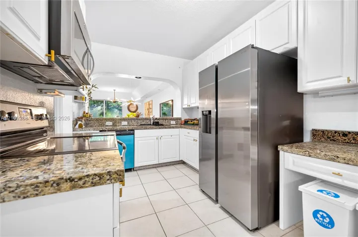 Kitchen featuring white cabinetry, stone countertops, tile flooring, and stainless steel appliances