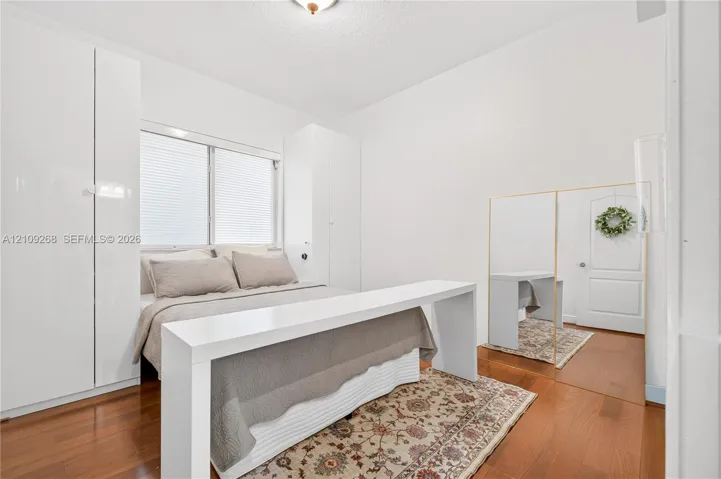 Room featuring high-gloss white built-in cabinetry, wood-finish flooring, a flush-mount ceiling light, and a white interior door
