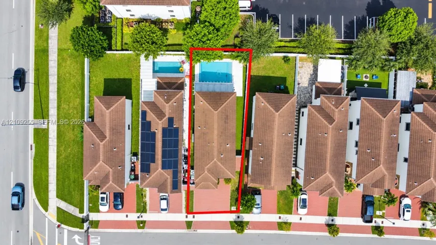 Aerial perspective featuring a private swimming pool, screened-in enclosure, paved driveway, and established landscaping