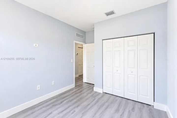 Interior space featuring light-toned walls, wood-finish flooring, and a multi-panel bi-fold closet door