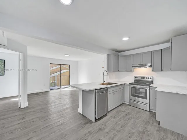 Kitchen featuring grey shaker-style cabinetry, stone-pattern countertops, stainless steel appliances, and wood-finish flooring